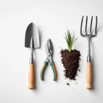 Tuingereedschap symmetrisch gerangschikt van bovenaf: chromen spade, snoeischaar en hark op wit beton met groen gras en aarde.