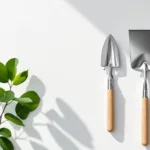 Tuingereedschap symmetrisch gerangschikt: snoeischaar, schepje en hark met verse bladeren op witte achtergrond